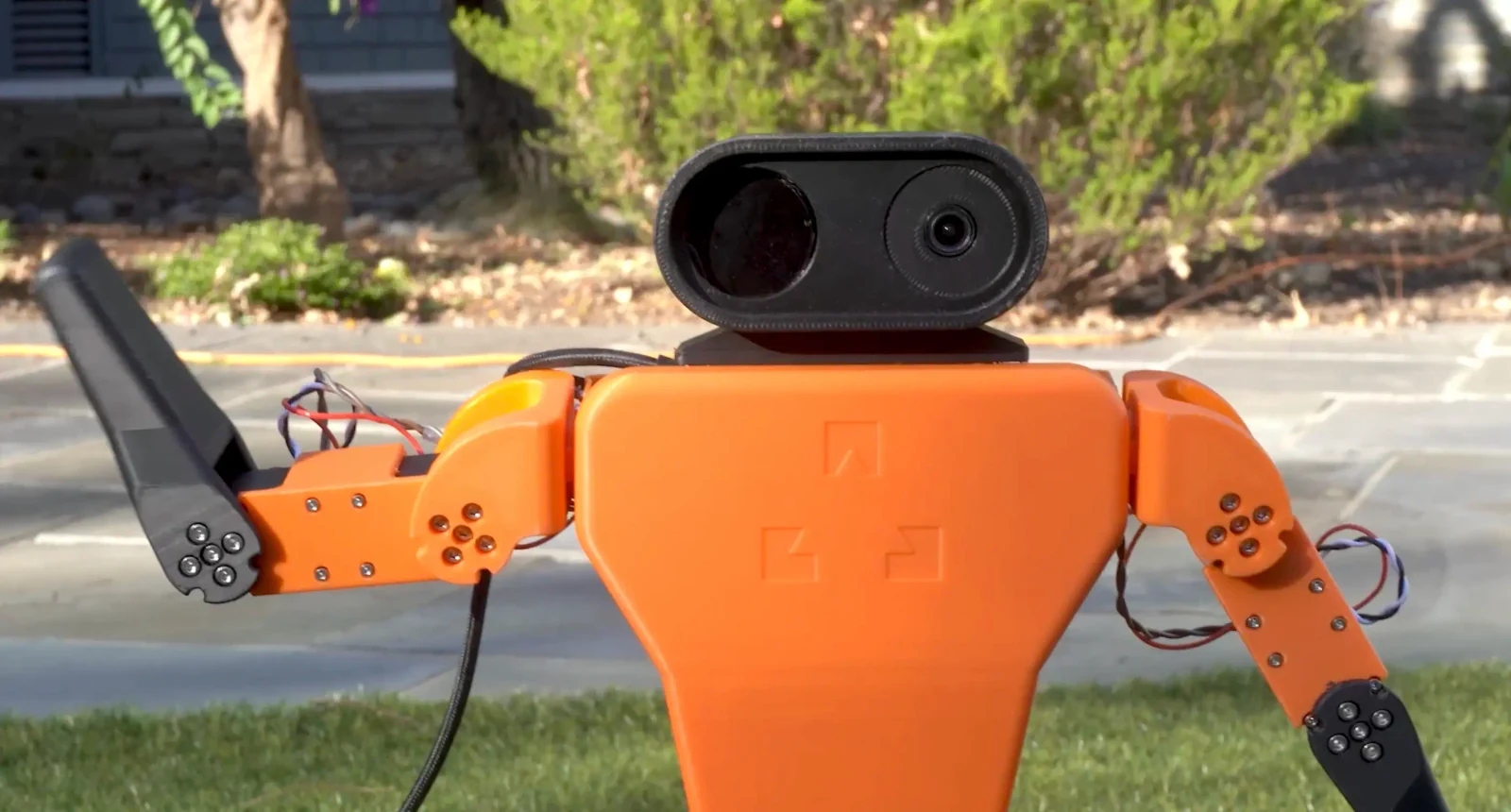Z-Bot small humanoid waving outdoors, orange printed shell