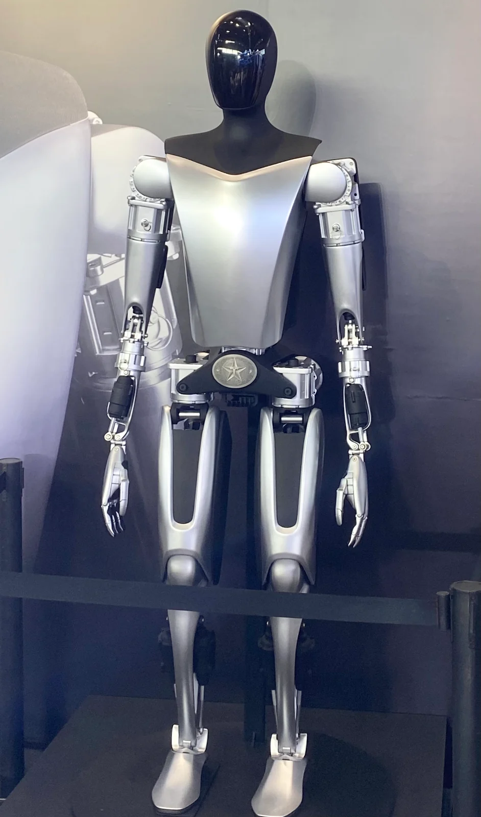 Tesla Optimus humanoid standing in an exhibition case, front view